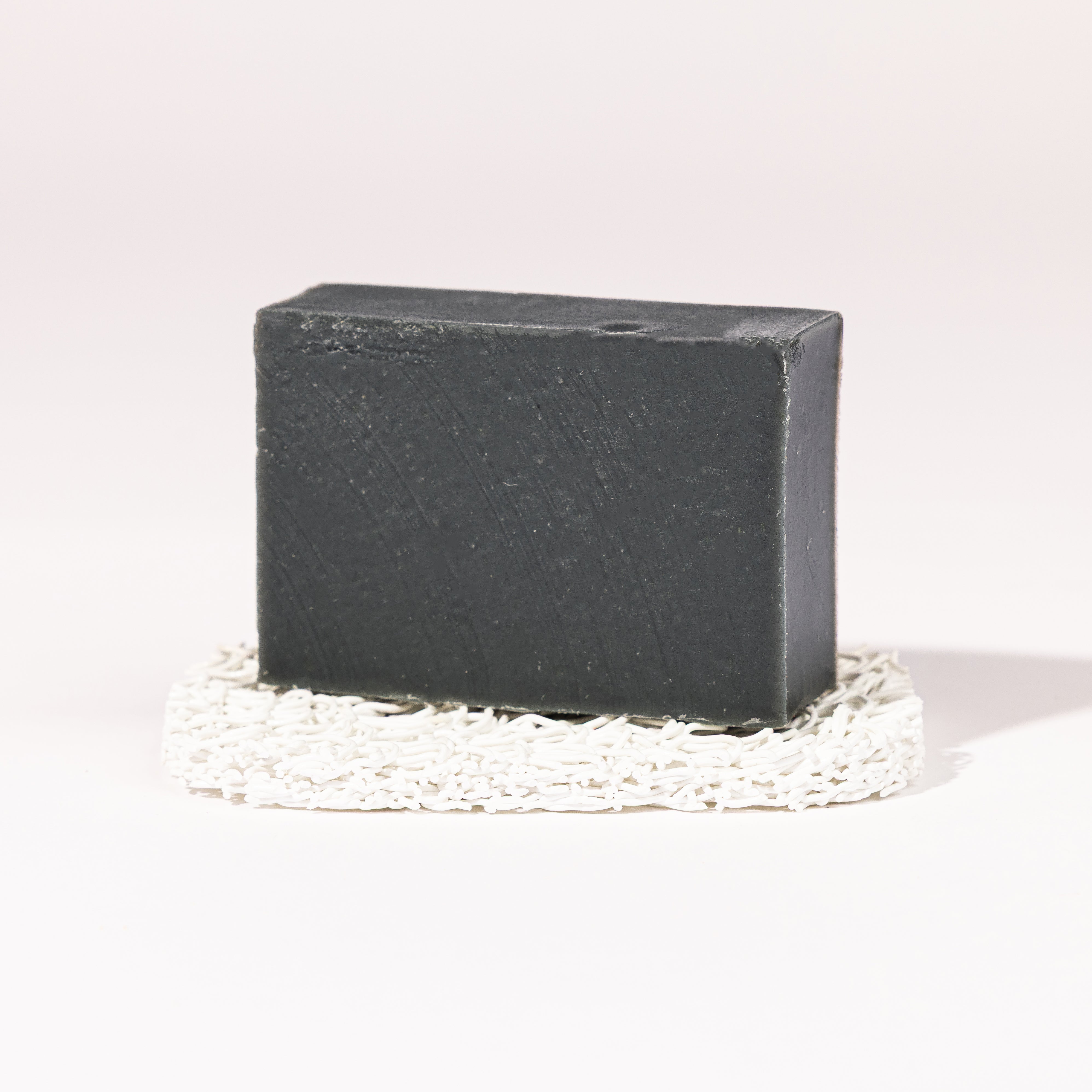 Madd House Hill Udder Maddness Charcoal Tea Tree Goat Milk Soap — unwrapped bar on soap lift, handmade hand cut all-natural goat milk soap, 4.5 oz